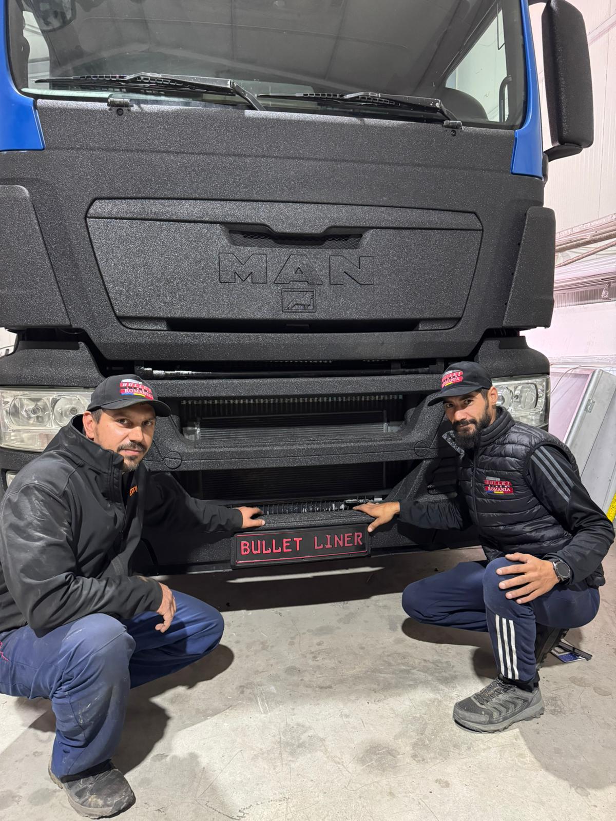 Echipa Bullet Liner lângă un cap tractor protejat, într-un cadru real de atelier.